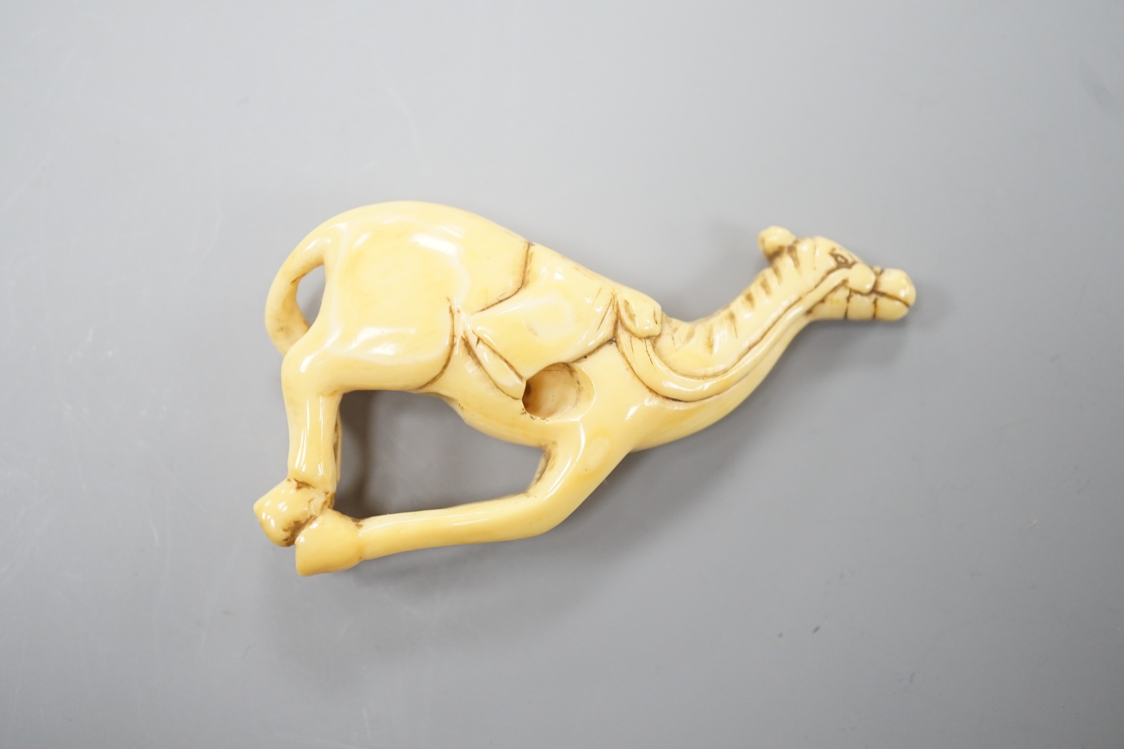A Japanese ivory netsuke of a horse, late 18th/early 19th century, lacking rider and re-shaped at the saddle, 6cm
